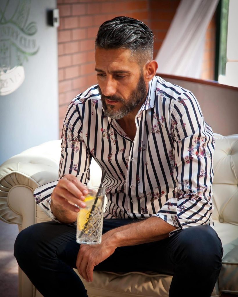 ストライプ×小花柄のイタリア製シャツを着こなす大人の男性。黒パンツと合わせた上品な柄シャツスタイル