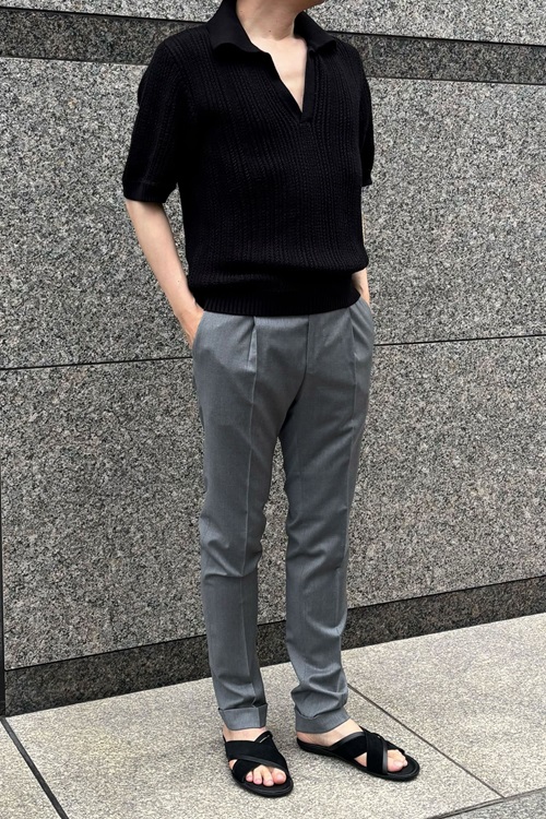 グレーのスラックスとスキッパーニットとレザーサンダルを着た男