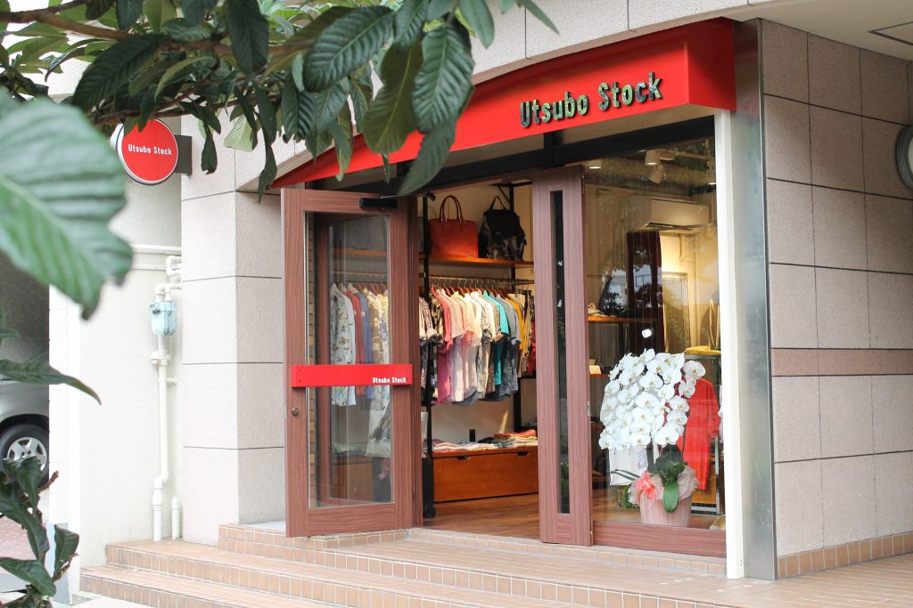 Utsubo Stock大阪店の外観。赤い看板と木製ドアが印象的な、イタリアブランドのメンズウェアを取り扱うセレクトショップ