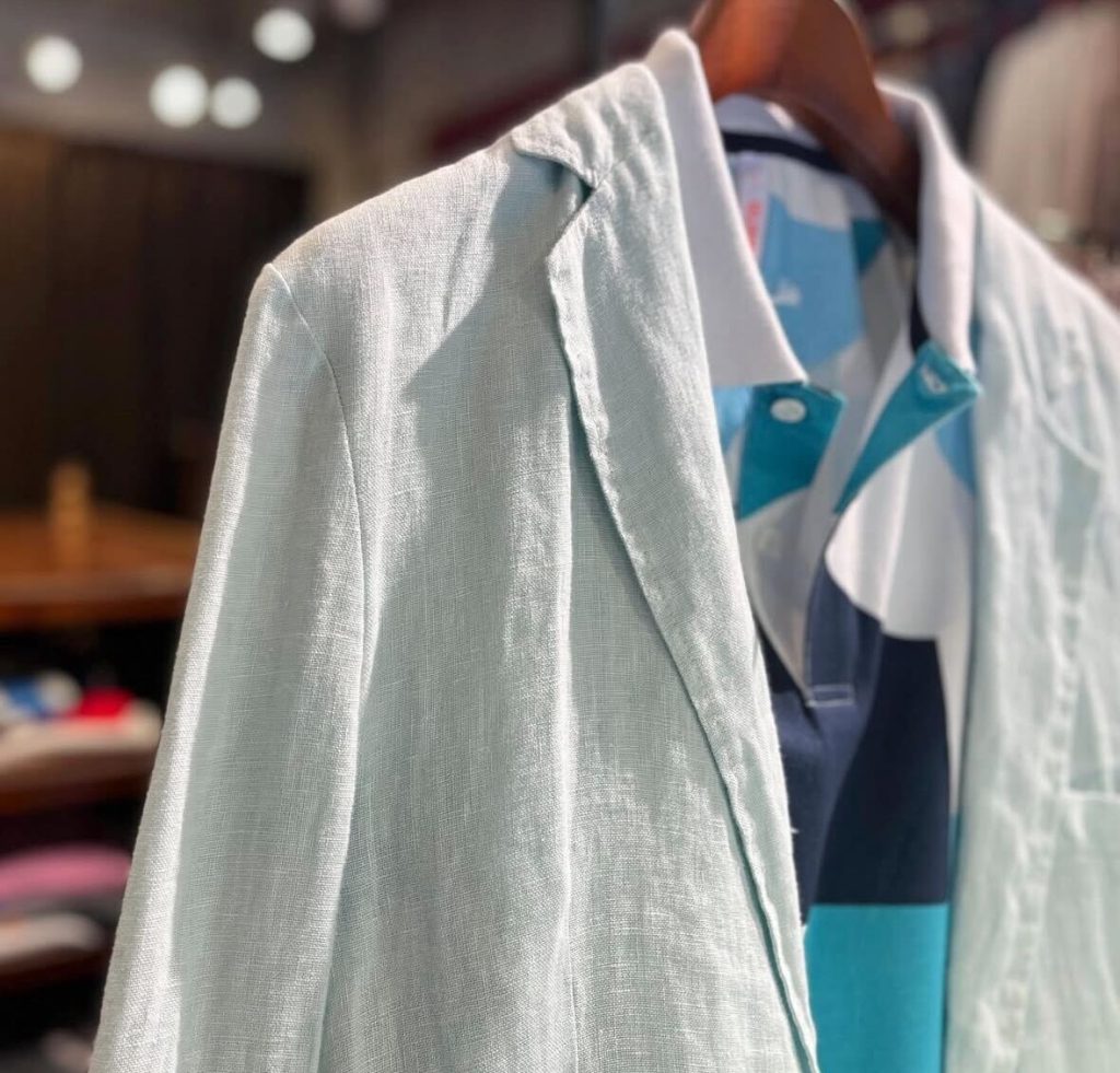 サックスブルーのリネンジャケットに太ボーダーのポロシャツを合わせた、初夏のイタリアンメンズファッション。通気性と爽やかさを両立した5月の装い。