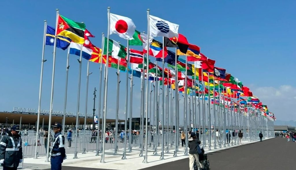 2025年大阪万博会場入り口付近。各国国旗が風にたなびかれている様子。