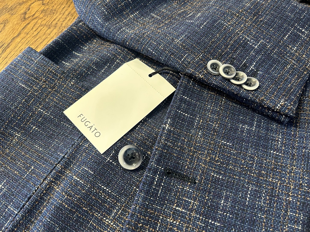  FUGATOのネイビー系サマーツイードジャケットの袖口ディテール。4つの飾りボタンとブランドタグが見える。