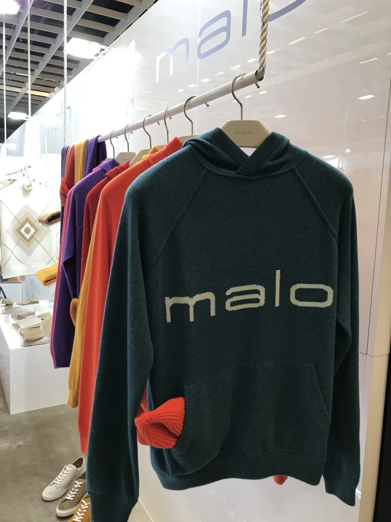 maloロゴ入りフーディとカラフルなニットが並ぶ店内ディスプレイ