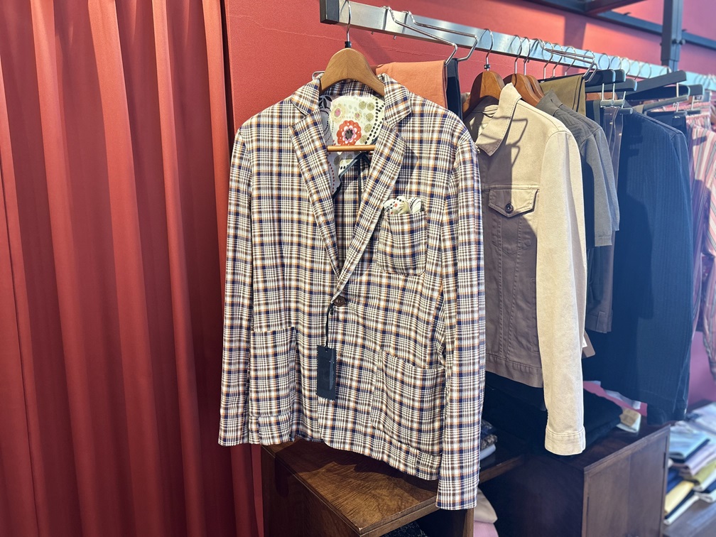 ポケットチーフが覗くNEILL KATTERのチェック柄ジャケット。ネイビー×オレンジの上品な配色