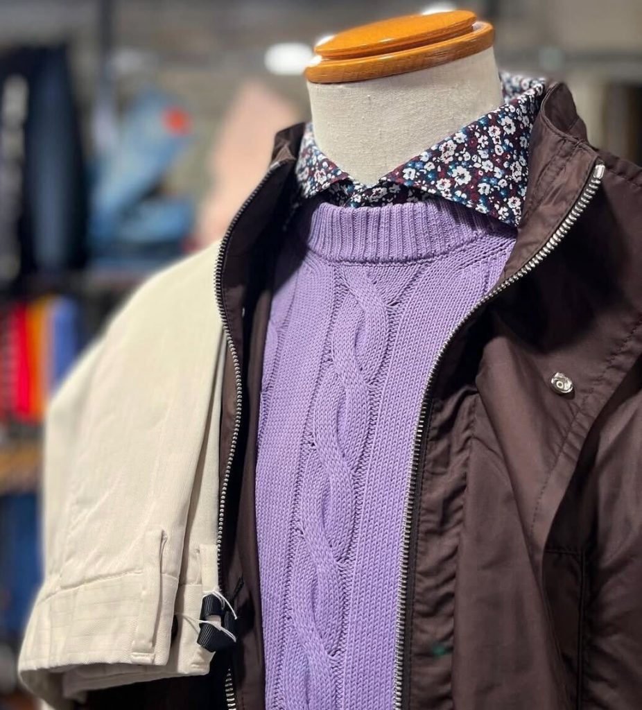 ラベンダーカラーのケーブル編みニットとフラワープリントシャツをレイヤードした春のイタリアメンズファッションコーデ。軽量ナイロンブルゾンを羽織った3月の装い。