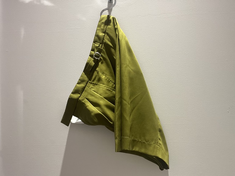 ドレープ感のあるロベルト・コリーナのオリーブグリーンのハーフパンツを壁にかけた様子