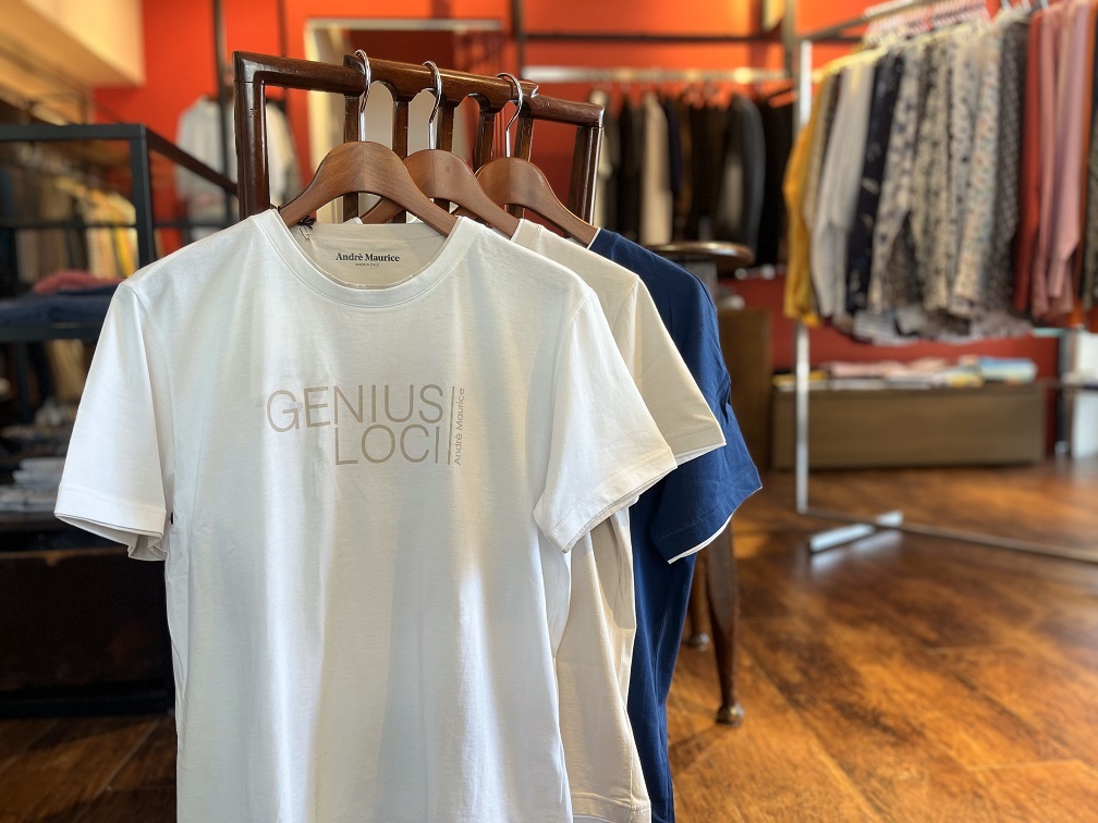 ANDRÉ MAURICEのロゴ入りプリントTシャツを店頭ラックに並べた様子。ホワイト・ネイビーなど複数色展開