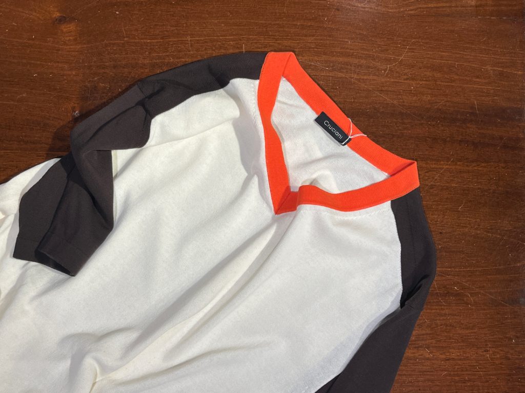 CRUCIANI（クルチアーニ）の配色ニットTシャツ。首元のオレンジがアクセントになった洗練デザインで、大人のカジュアルにぴったり。