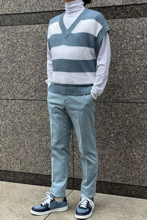 etroのネイビースニーカーを履いたカジュアルコーディネート。白とブルーのストライプvネックセーター、ライトブルーのパンツ、白いタートルネックを合わせたスタイル。