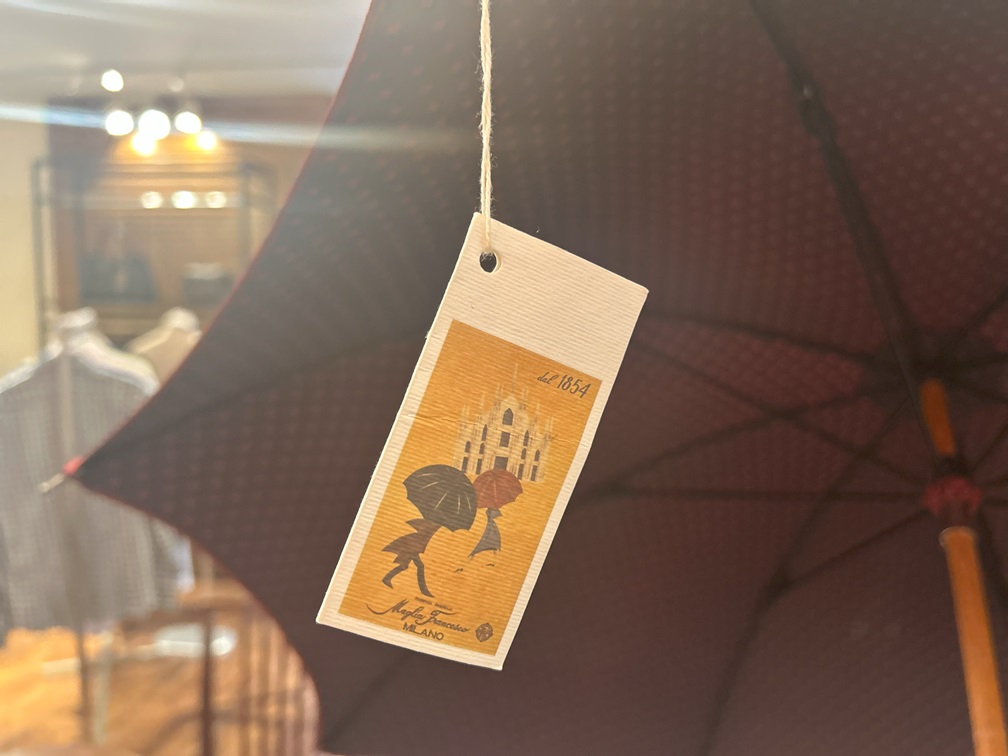 傘にぶら下がるブランドタグと赤黒花柄刺繍のクローズアップ