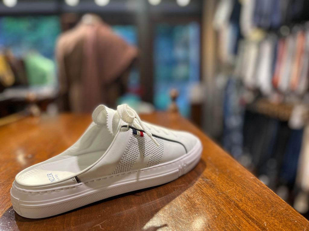 MONCLER（モンクレール）の白レザーサンダル。スニーカーライクなアウトソールと開放感あるデザインで、夏のジャケットスタイルに抜け感をプラス。