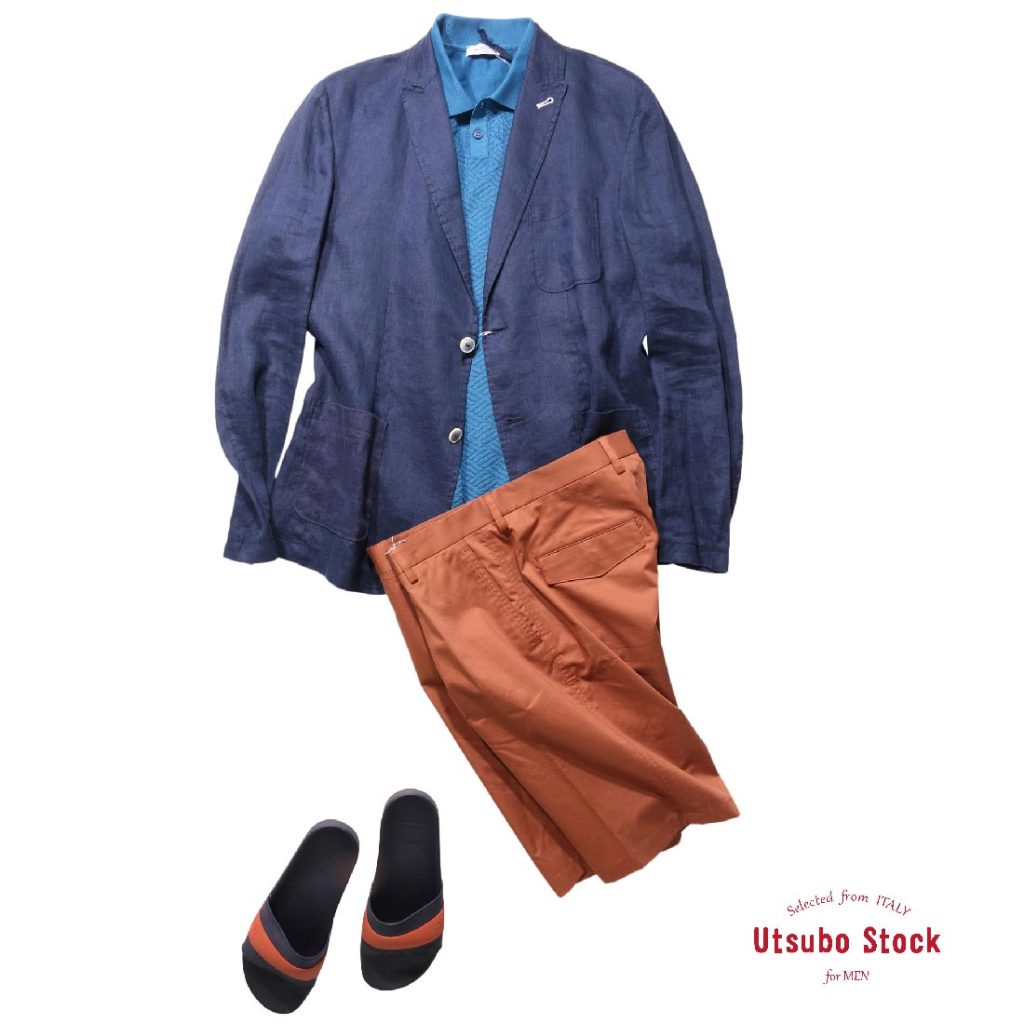 ネイビーのジャケットとターコイズブルーのニットポロに、オレンジのパンツとサンダルを合わせた、リラックス感のある夏のジャケパンスタイル。