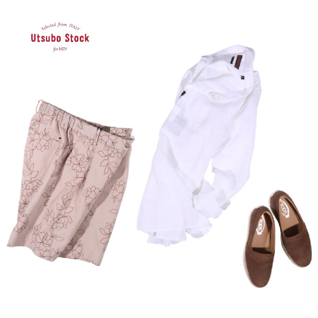 OUTFITの花柄ショーツと白リネンシャツ、ブラウンスリッポンを合わせたリゾートスタイル。