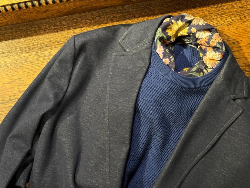 +39 masqのネイビージャケットに、花柄のインナーとリブ編みニットを重ねた遊び心あるスタイリング。華やかさと落ち着きが共存した着こなし。