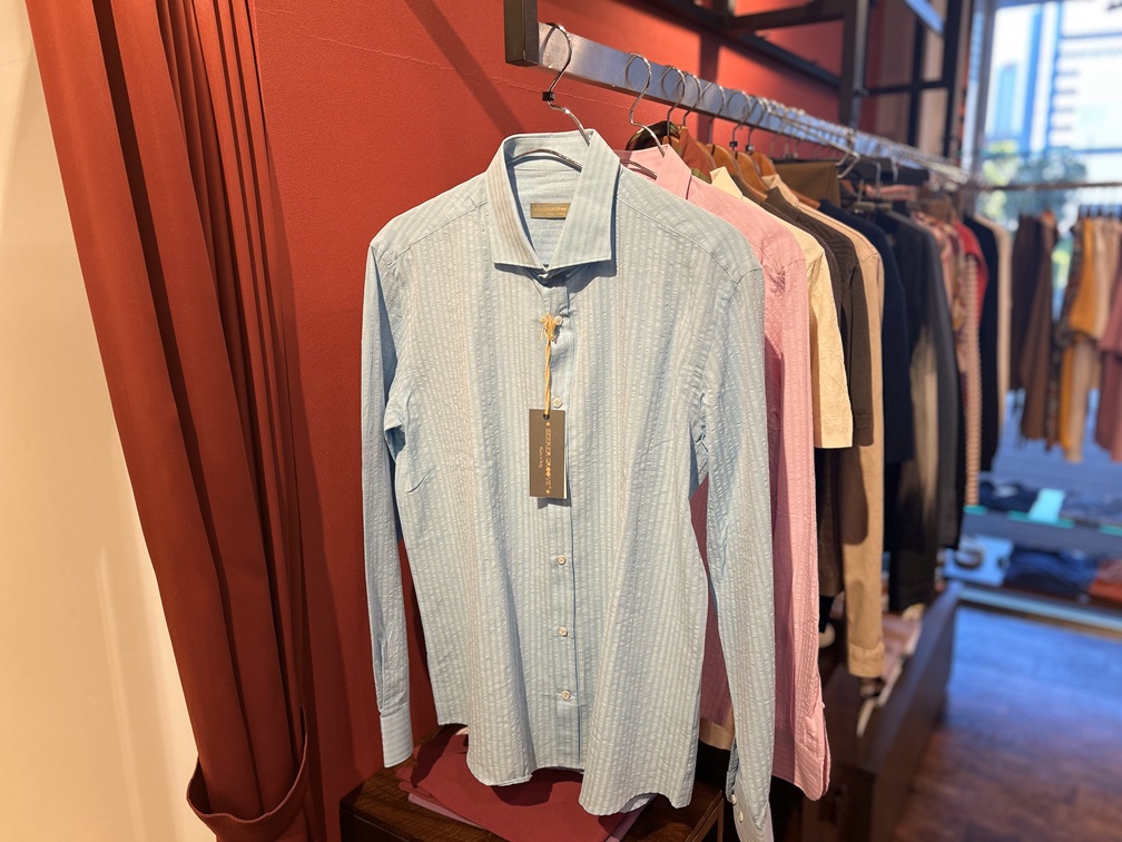 SEEKER GROOVEのシアサッカー素材ブルーシャツが店内で吊り下げられている様子