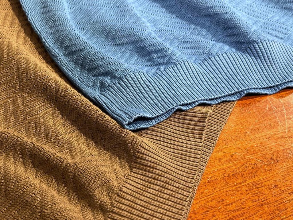 Wool & Coのサマーニットの裾部分をクローズアップした画像。立体感のある幾何学編みとリブ仕立ての切り替えが美しく、ブラウンとブルーのコントラストが際立つ。