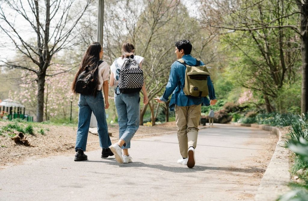 公園を歩く学生たちの後ろ姿。進路を模索する若者のイメージ。