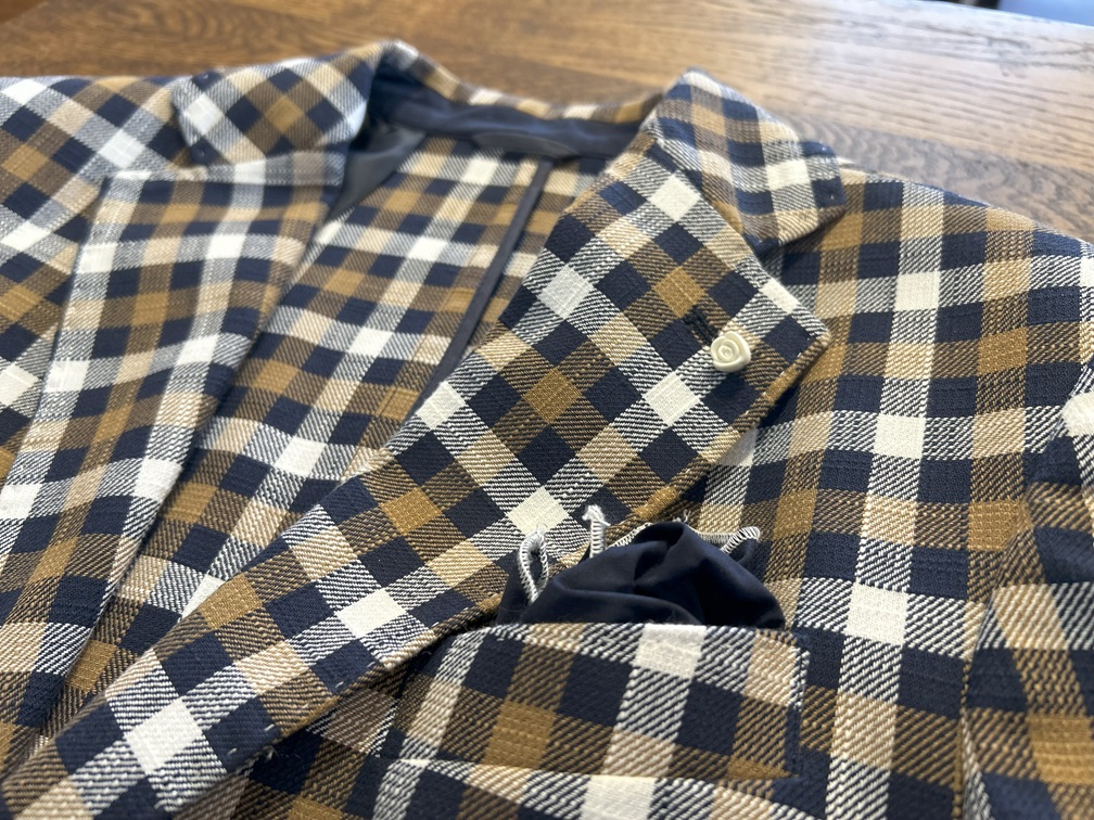 ホワイトパイピング付きチーフとバラ型ラペルピンのディテール