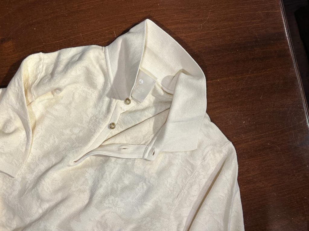 AT.P.COのクリーム色ジャカード柄ポロシャツを前身ごろから捉えた画像。上品な模様とコットン混ジャカード生地の質感が映える一枚。