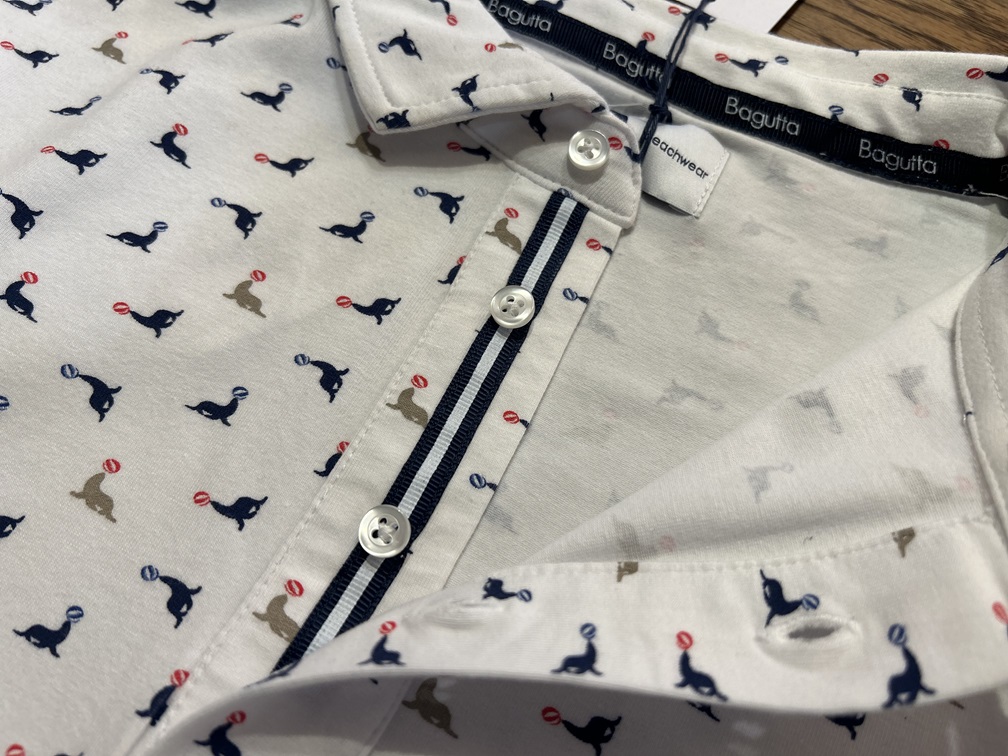 BAGUTTAのホワイトのアシカ柄ポロシャツ。ネイビーテープがボタン周りを引き締める