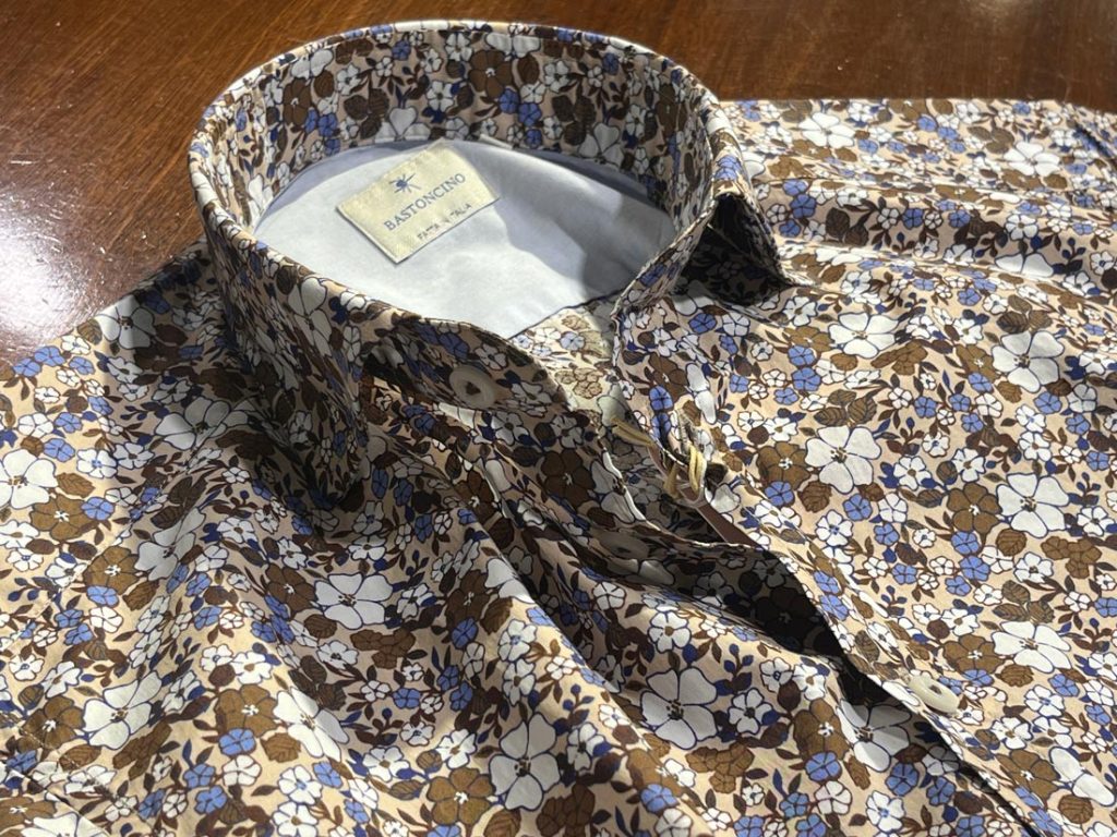 《BASTONCINO（バストンチーノ）》のブラウン×ブルー系フラワープリントシャツ。襟元とボタン部分の丁寧な仕立てが際立つ1枚。