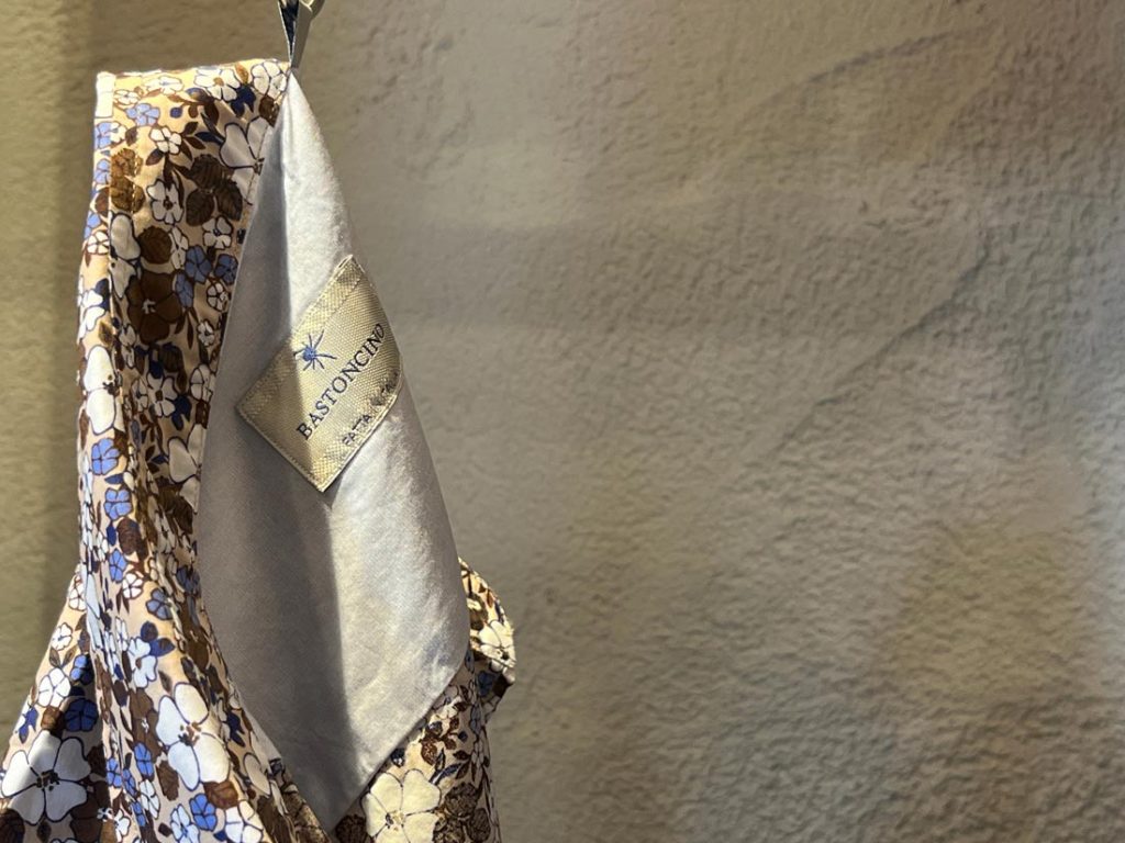 《BASTONCINO（バストンチーノ）》のフラワープリントシャツの内タグが見えるアップ画像。繊細な縫製と柔らかな色味が特徴。