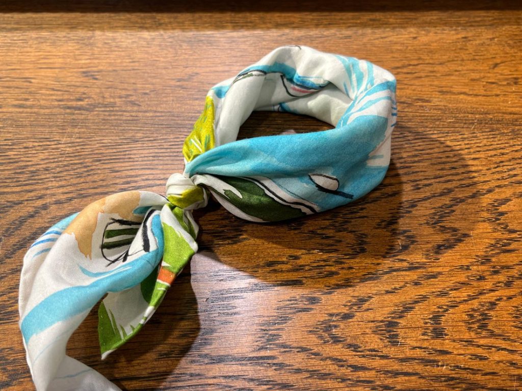 ターコイズブルーとホワイトの爽やかな配色が映えるスカーフ。