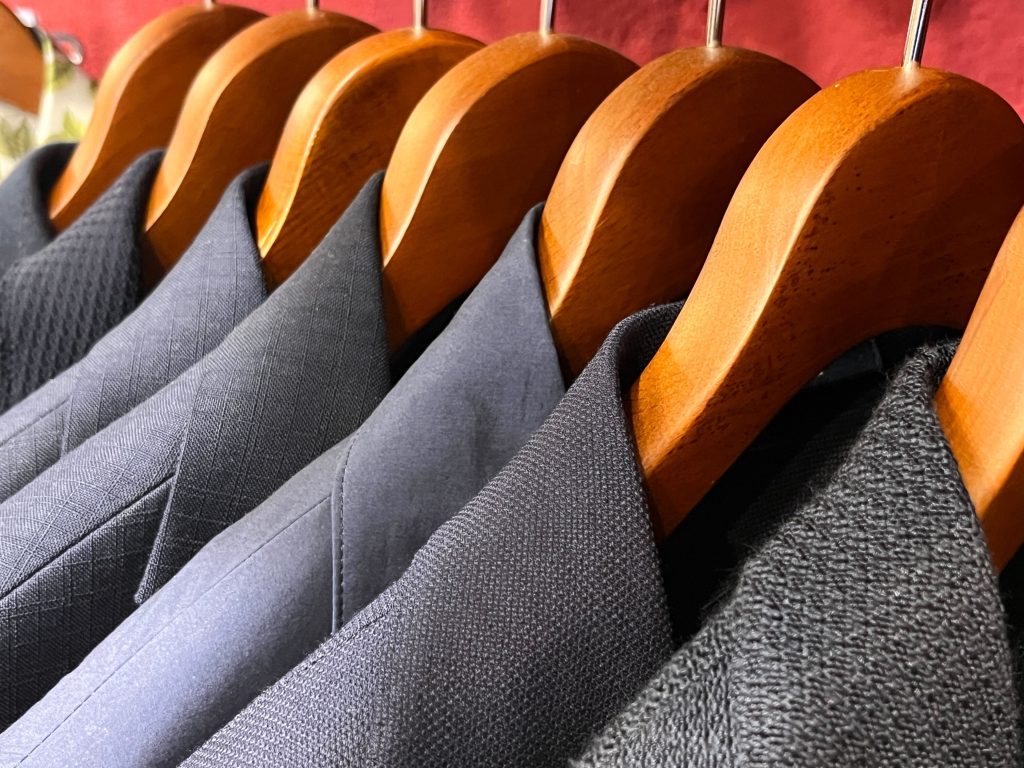 木製ハンガーにかけられた上質なイタリア製ジャケットが並ぶ店内の様子。多様な生地の質感が美しく、クラシックで洗練された印象を与える。