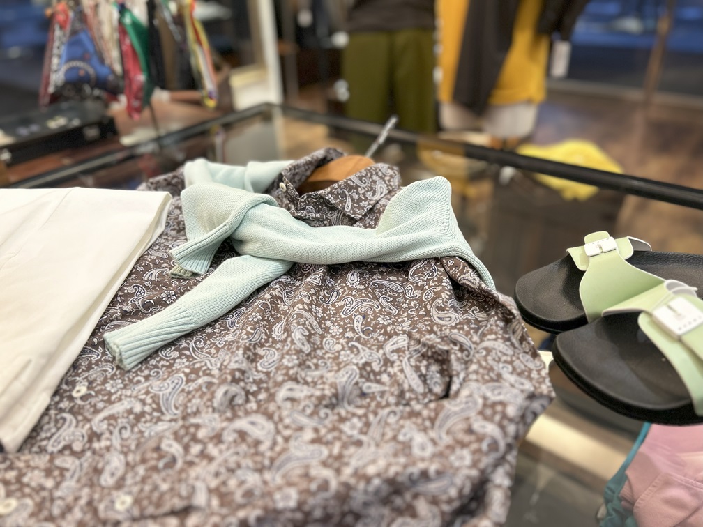 POGGIANTI 1958 ブラウンベースのペイズリー柄シャツにミントカラーのニットを肩掛けし、サンダルを合わせたコーディネート