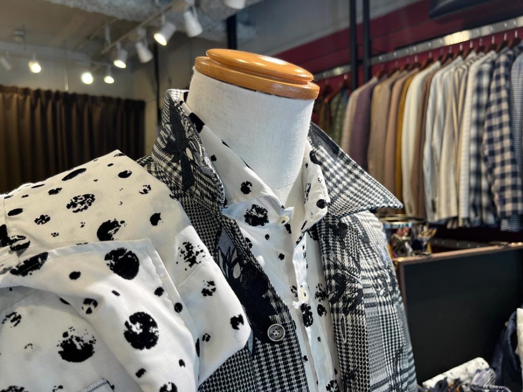 POGGIANTI 1958の白地に黒のモノトーンパターンが映えるシャツと、チェック柄のモノトーンジャケットのレイヤードスタイル