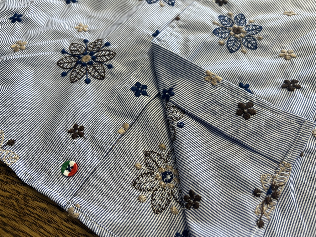 ブランドロゴ入りボタンと花柄刺繍が特徴の裾部分ディテール
