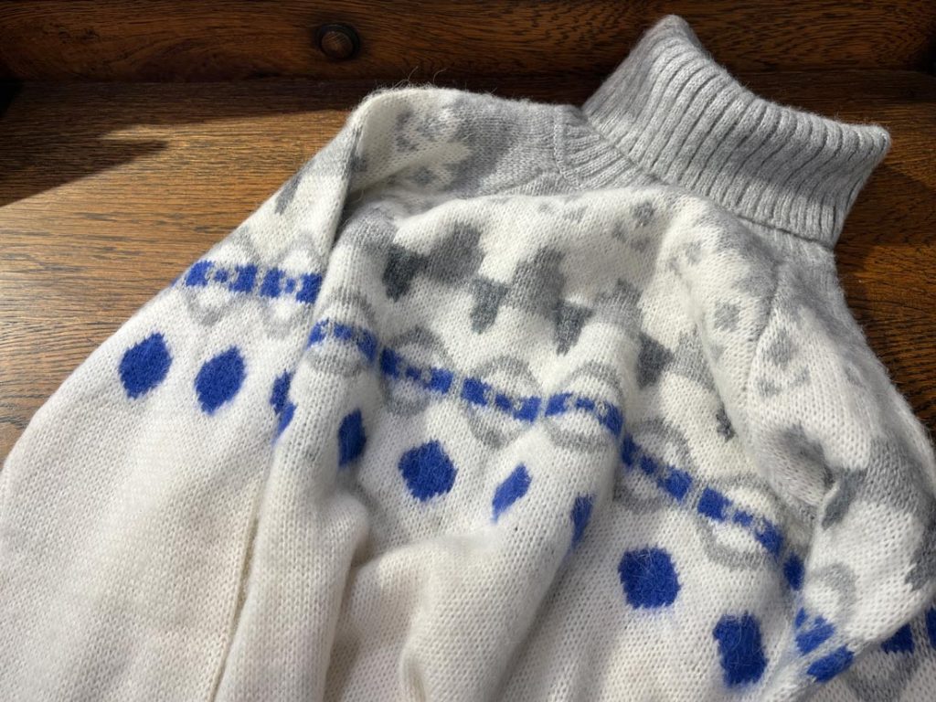 PRIVATIのノルディック柄ハイネックニット。ホワイトベースにグレーとブルーの幾何学模様が配された秋冬らしい一枚。