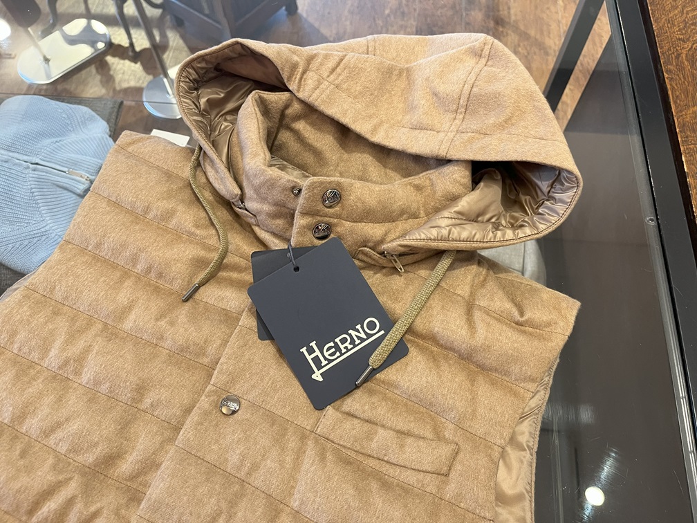 HERNOのロゴタグが付いたキャメルカラーのダウンベスト