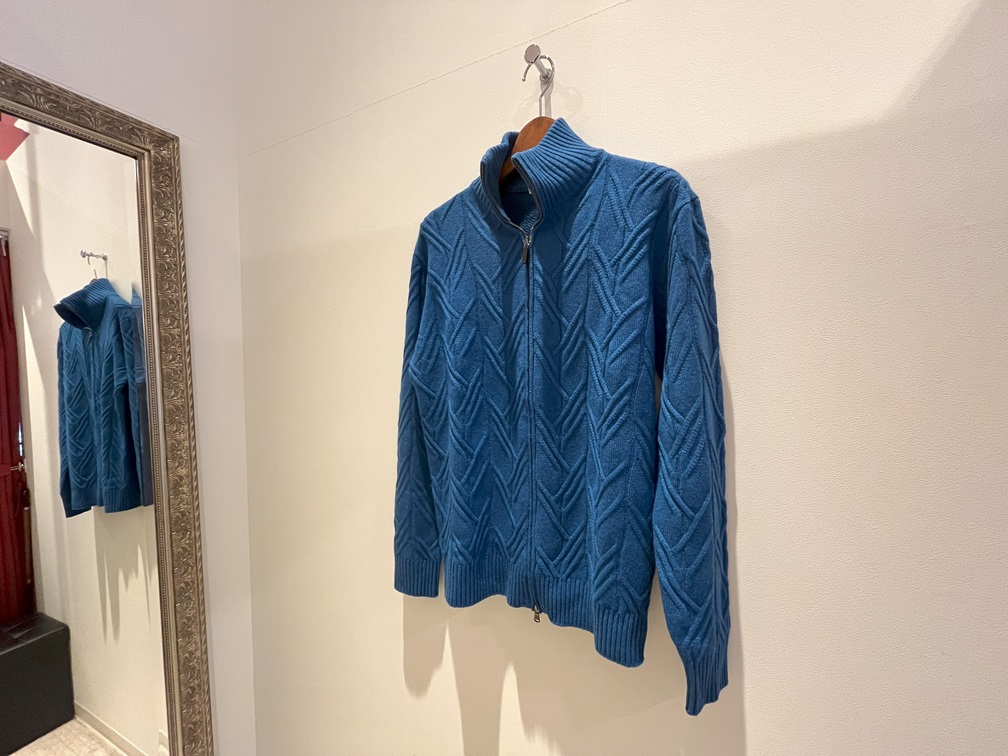 壁掛けでディスプレイされたブルーのジップアップブルゾン