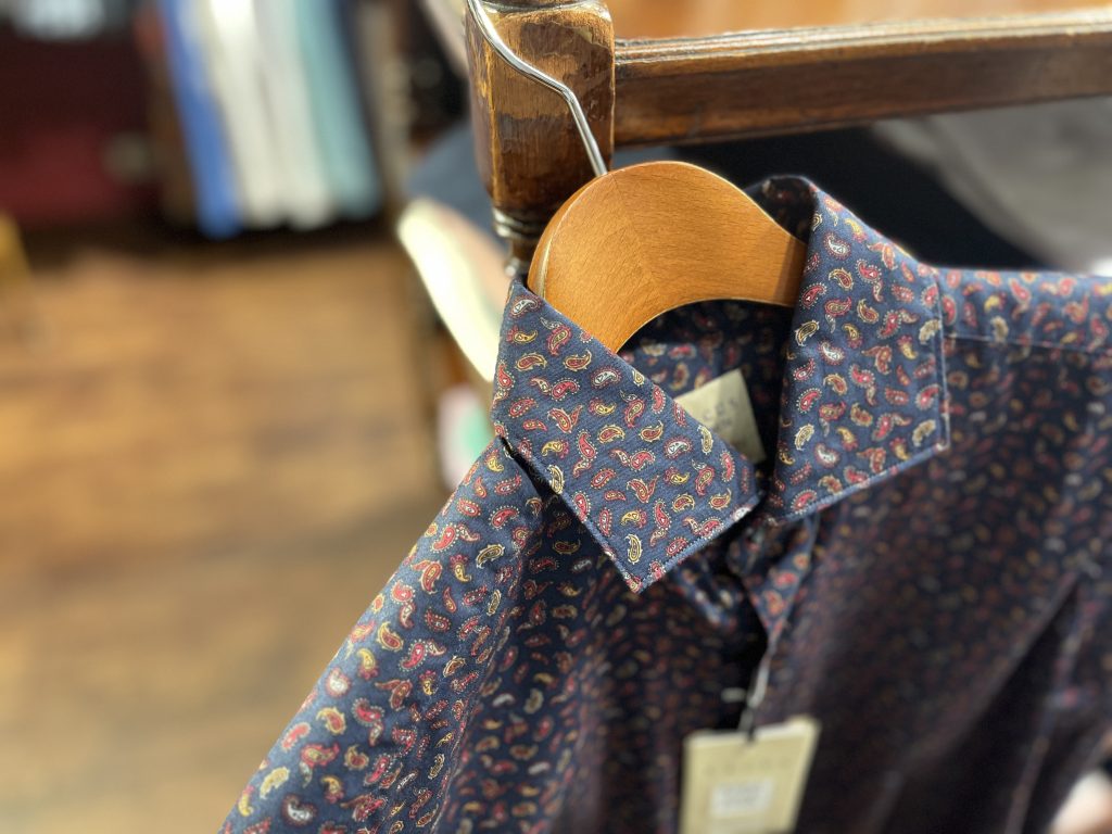 XACUSのペイズリー柄シャツ。深みのあるネイビーベースに華やかなペイズリープリントが施された大人の一枚。