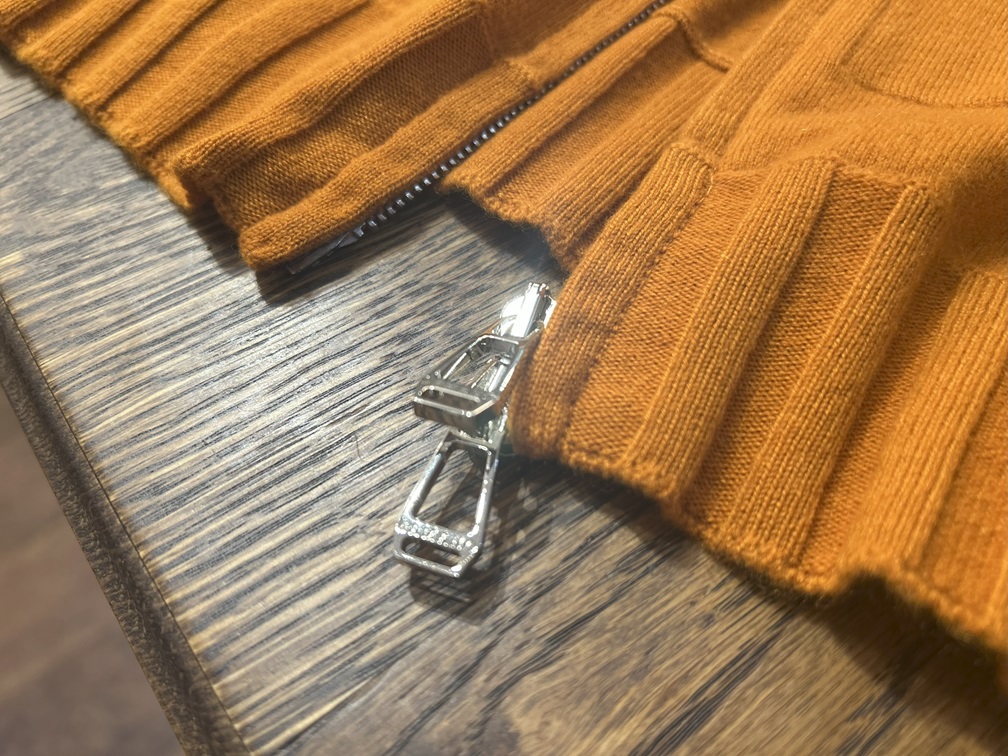 シルバーのダブルジップ引き手が光るカシミヤニットの先端ディテール