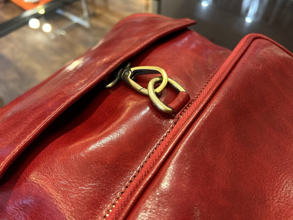 フラップ部分の金具が映えるレッドレザー