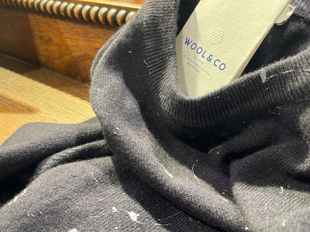 WOOL&COのブランドタグが映えるペイントニットの首元アップ