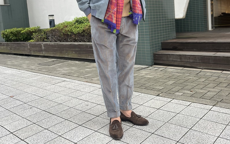 ブルーのコーデュロイパンツにスエードブルゾンを合わせたコーディネート(アップ)。柔らかなトーンが秋冬の装いに軽やかさをプラス。