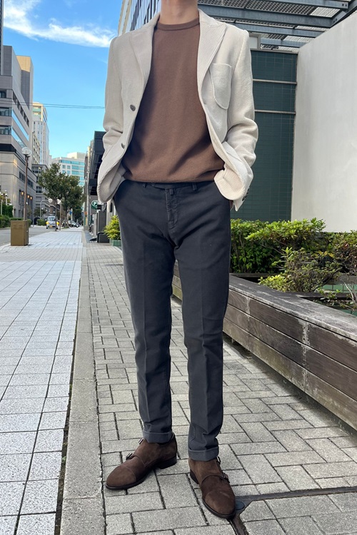 アイボリーのコーデュロイジャケットにブラウンのクルーネックニットを合わせた上品なスタイル。異素材の組み合わせが温かみと立体感を演出。