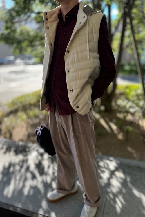 ベージュのダウンベストにボルドーコーデュロイシャツ、ベージュベロアパンツを合わせた秋冬コーデ。柔らかい素材感と落ち着いた色味が上品な印象を与える。