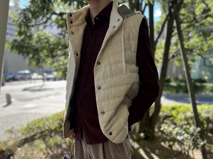 ベージュのダウンベストにボルドーコーデュロイシャツ、ベージュベロアパンツを合わせた秋冬コーデ(アップ)。柔らかい素材感と落ち着いた色味が上品な印象を与える。