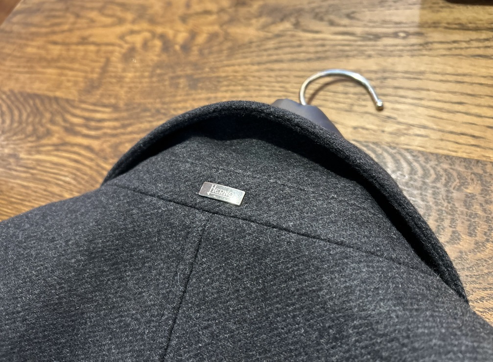 HERNOチェスターコートの襟裏に配置された上品なブランドロゴプレート