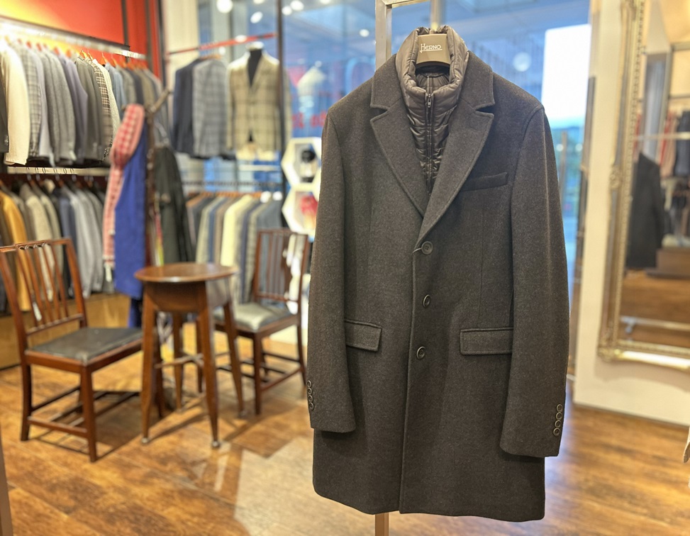 店内で吊るされたHERNOのチャコールグレーチェスターコートの全体シルエット