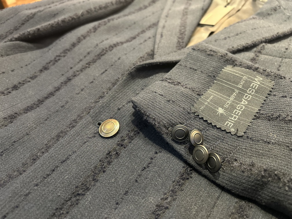 ブロンズボタンと織り柄が特徴のMESSAGERIEブラックジャケット