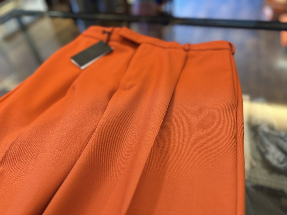 フロントプリーツが際立つPT TORINOオレンジパンツの生地アップ。ギャバジン特有の光沢を表現。