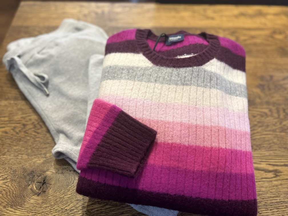 グレーパンツの上に丁寧に畳んだDrumohrマルチボーダーニットを写した上質感のあるスタイリング写真