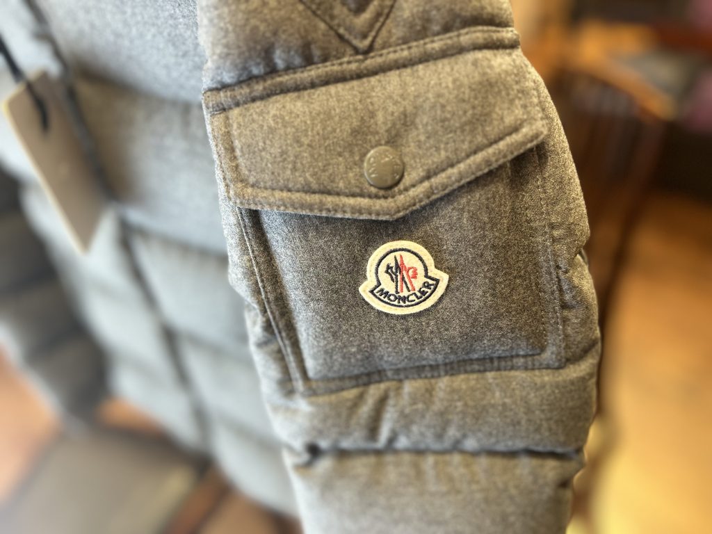 「モンクレール ダウンのアームポケットに施されたブランドロゴパッチのディテール」