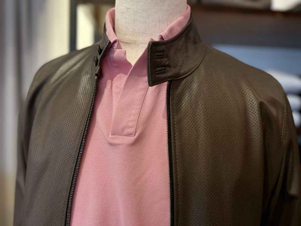 ピンクのポロシャツにブラウンレザージャケットを合わせた大人コーデ